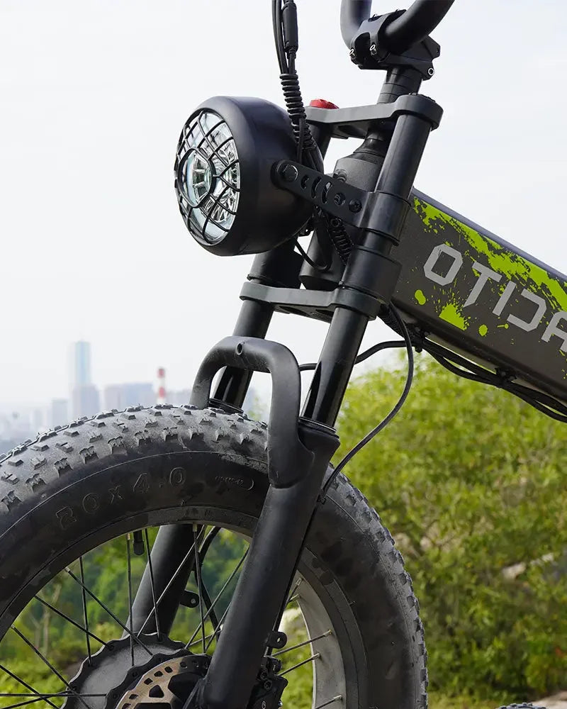 Close-up of a black OTIDA R7 MAX Dual Motor Electric Bike with a cityscape in the background