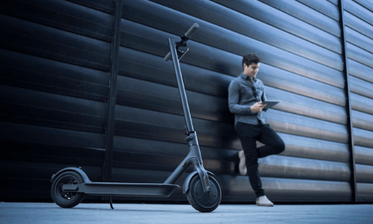 black electric scooter side view in urban setting with person leaning against wall