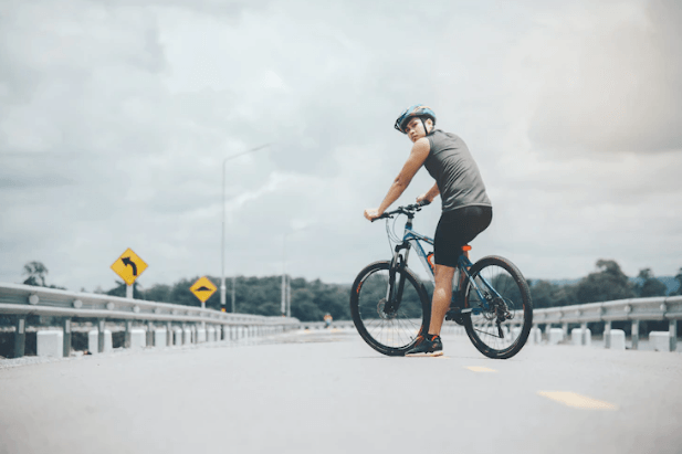 Electric bike in matte black with rider, side view, on an open road outdoors