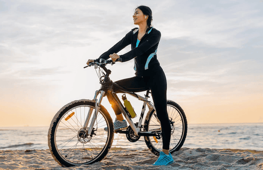 Electric bike with woman rider on a sandy beach at sunset, side view