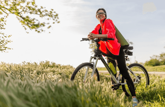 Electric bike with front suspension on grassy trail, side view with rider in outdoor setting